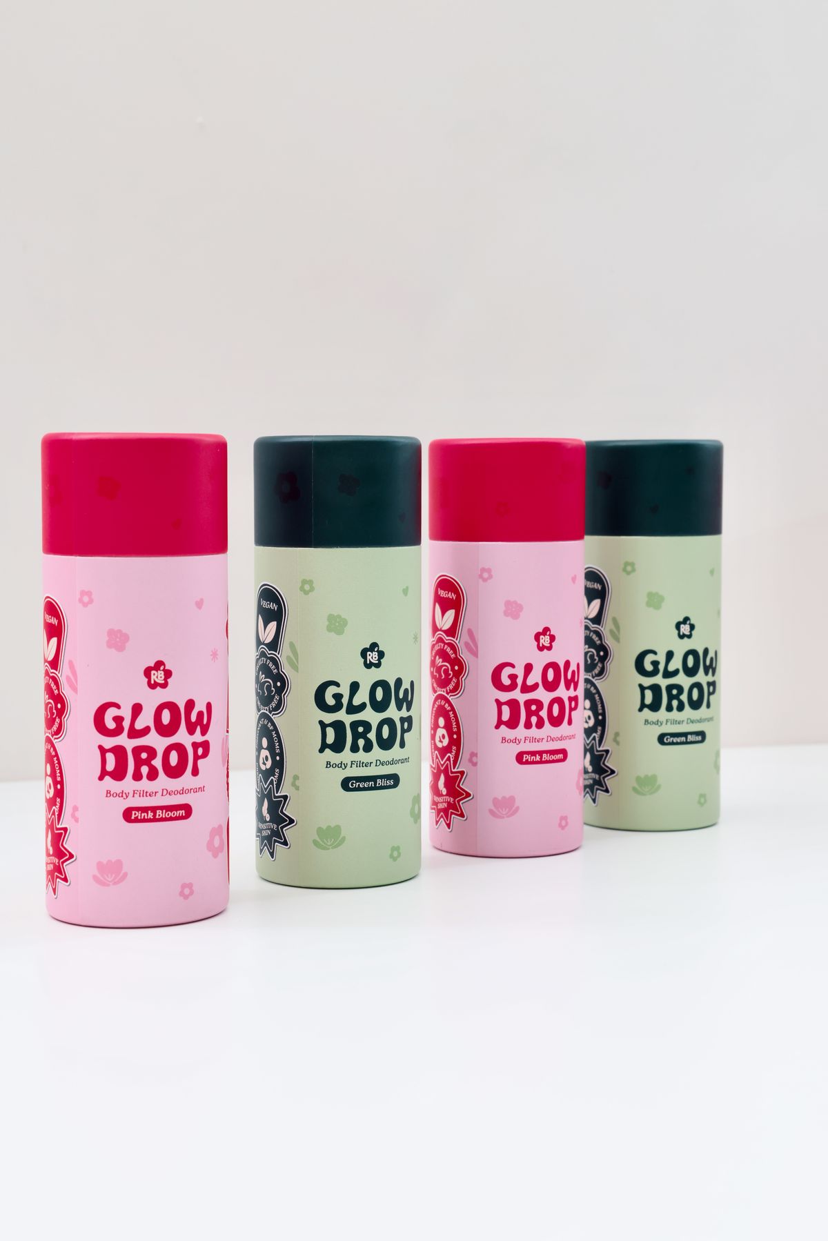 Four Glow Drop deodorant tubes in alternating Pink Bloom and Green Bliss