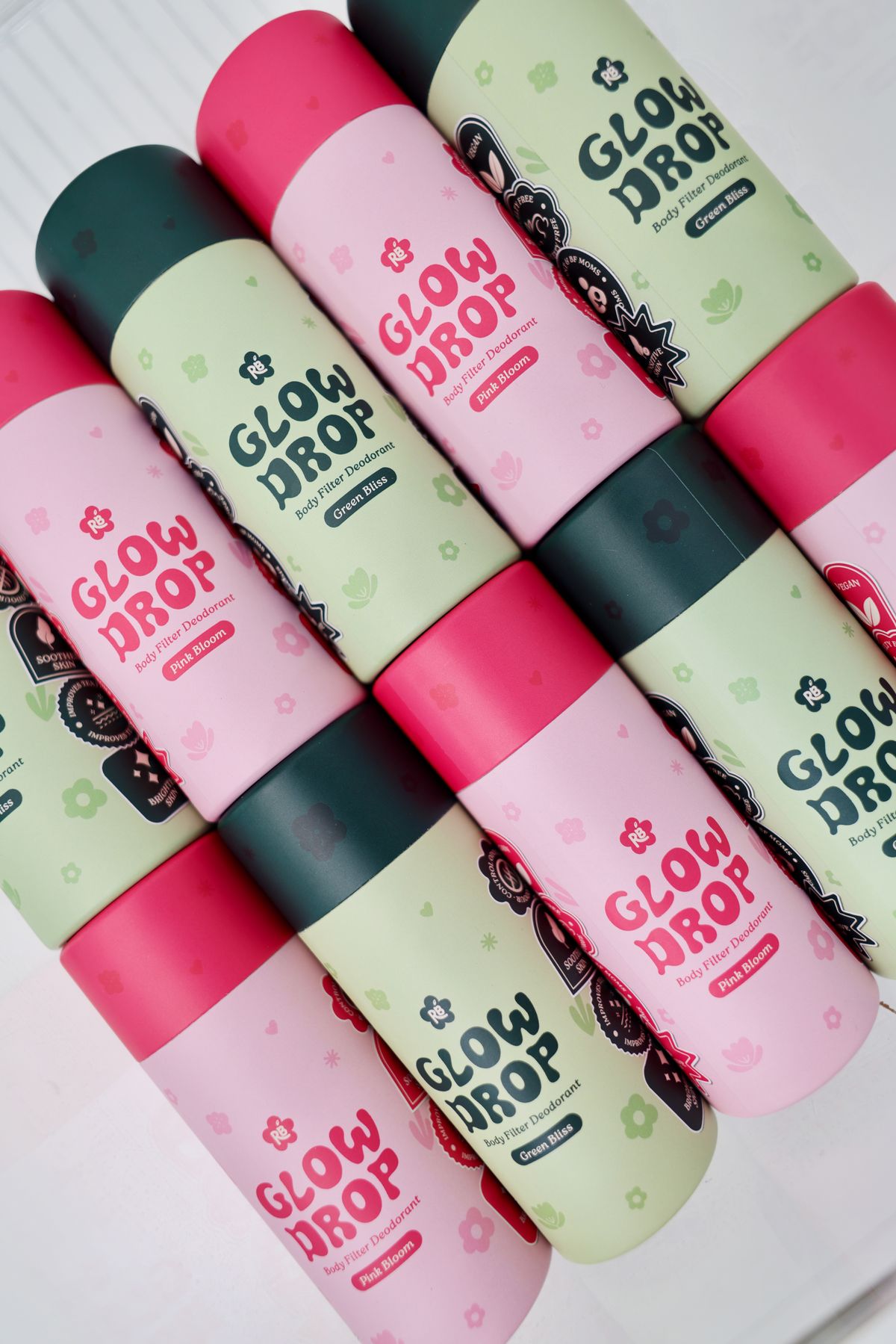 Glow Drop deodorant tubes stacked together in pink and green